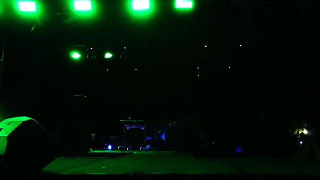 Bright green lights illuminating outdoor concert stage at night