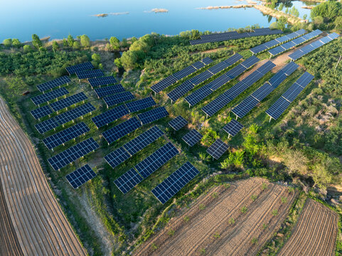 Solar photovoltaic power station on hillside with lake and farmland landscape