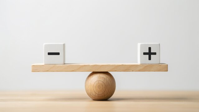 Wooden balance scale with a plus and minus sign cube on a flat surface