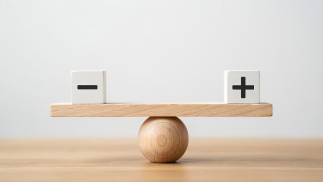 Wooden balance scale with a plus and minus sign cube on a flat surface