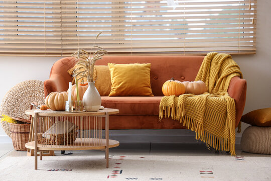 Creepy living room with orange sofa, pumpkins and coffee table decorated for Halloween celebration