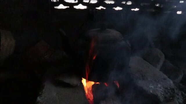 Footage of water boiling in an old metal kettle on a traditional wood fired stove inside a simple rural kitchen in Java, Indonesia. Authentic countryside cooking with natural firewood.