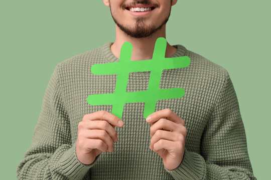 Man with hashtag sign on green background, closeup