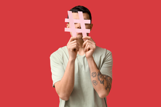 Young man with hashtag symbol on red background