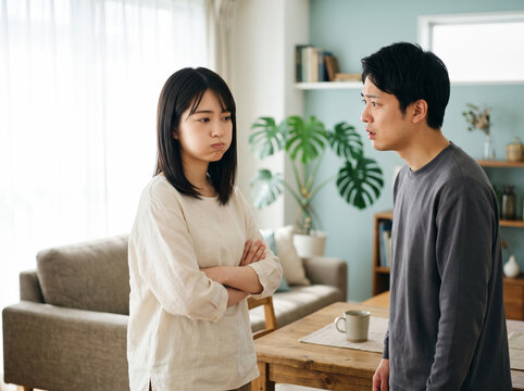 リビングでパートナーの男性と言い争いをしてふてくされる若い女性