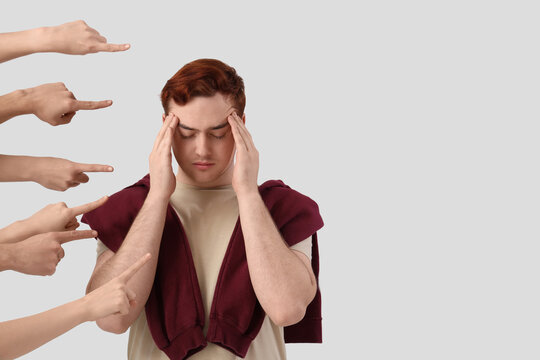 People pointing at stressed young man on white background. Accusation concept