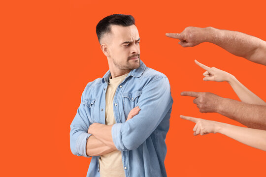 People pointing at young man on orange background. Accusation concept
