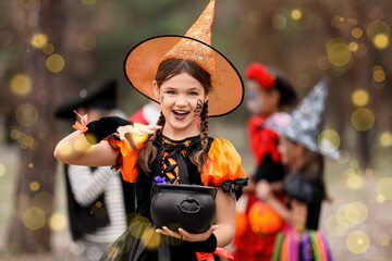 Obraz premium Smiling girl in witch costume holding Halloween bucket