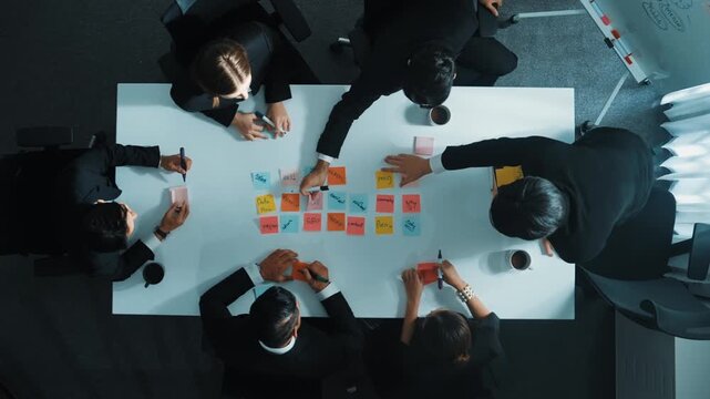 Top down aerial view of skilled diverse business group choosing marketing strategy while businessman standing and presenting project by using mind map at meeting room. Teamwork concept. Directorate.