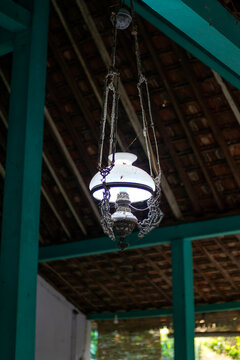 Dusty antique hanging lamp suspended under a wooden ceiling.