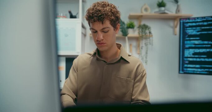 Young Caucasian male programmer working on coding in startup office workspace. Software developer artificial intelligence engineer technology, computer network digital system server security concept.
