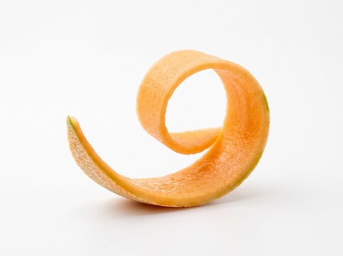 A single curved slice of fresh orange cantaloupe melon peel curled into a spiral shape