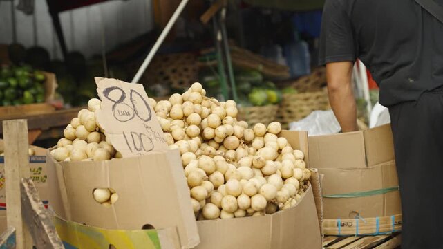 Fresh Langsat Display with Price Tags While Vendor Packs Fruit at Local Market