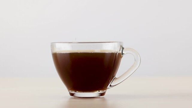 Pouring Instant Coffee Powder into a Clear Glass Mug