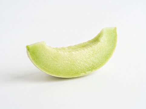 A single fresh slice of juicy ripe honeydew melon fruit with light green flesh and a firm texture