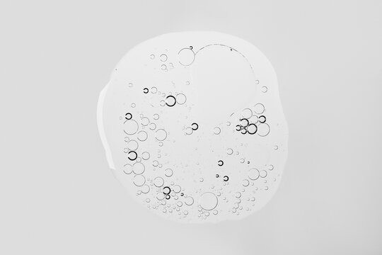 Transparent liquid blob with air bubbles on white background, abstract cosmetic texture