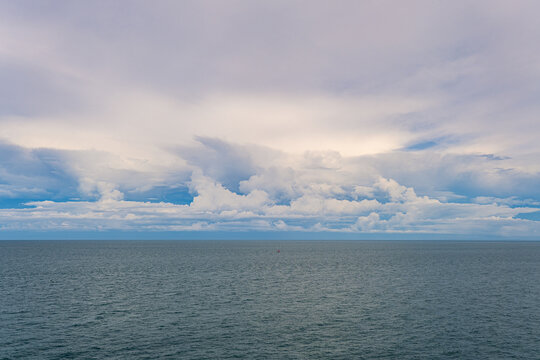 Expansive blue ocean beneath layered white clouds