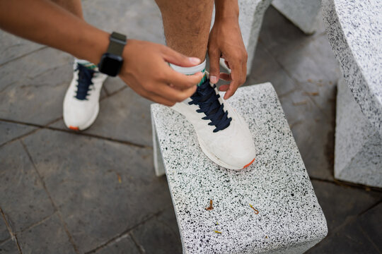 African American mixed race man tying running shoes before workout in urban park.