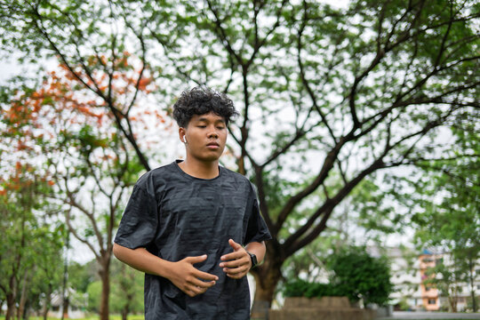 African American mixed race man jogging in green city park for wellness active and feel good lifestyle.
