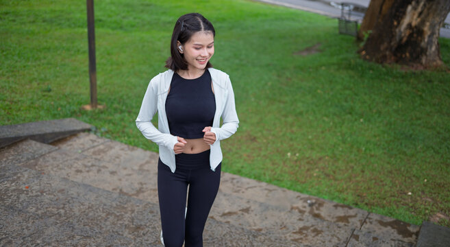 Asian Gen Z woman jogging in green urban park for wellness fitness and active city lifestyle
