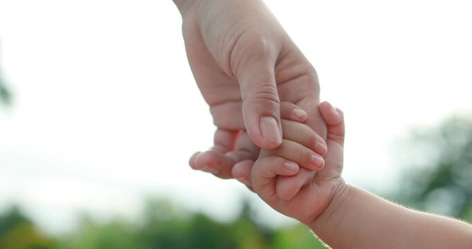 Adult holding a child hand, love and care, trust, protection, family bonding, parenting, safety, and emotional connection in natural outdoor light