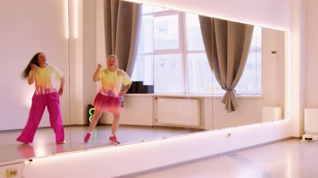 Festive dancer. Funny performance. Happy woman in bright colorful clothes expressive rehearsal moving in mirror light mirror studio.