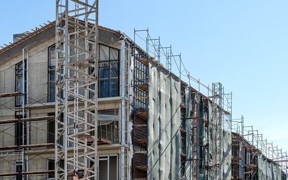 modern residential buildings with scaffolding under construction against blue sky background.