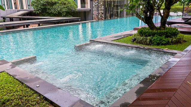 A swimming pool with a jacuzzi nestled among tropical greenery on the grounds of a residential condominium in Thailand. A refreshing atmosphere after the rains of the monsoon season.