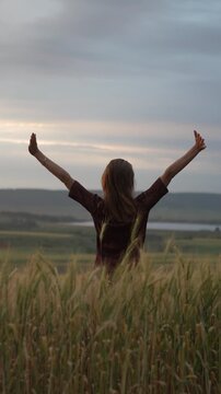 Woman wheat field standing in golden crop at sunset feeling calm and peaceful while enjoying nature in countryside during summer time