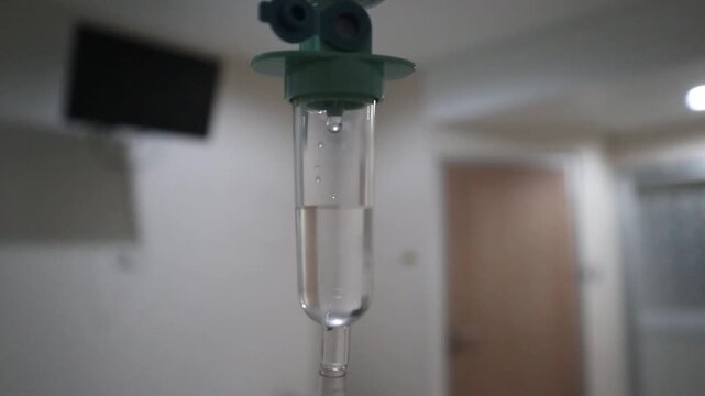 Defocus blur medical IV drip chamber in hospital room, intravenous infusion dripping in patient ward, healthcare and treatment concept.