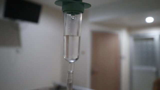 Defocus blur medical IV drip chamber in hospital room, intravenous infusion dripping in patient ward, healthcare and treatment concept.