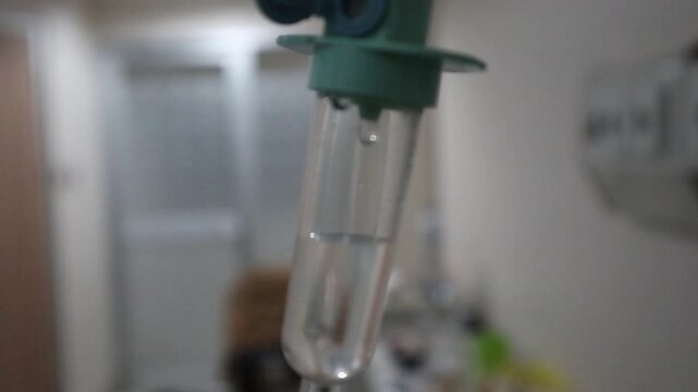 Defocus blur medical IV drip chamber in hospital room, intravenous infusion dripping in patient ward, healthcare and treatment concept.