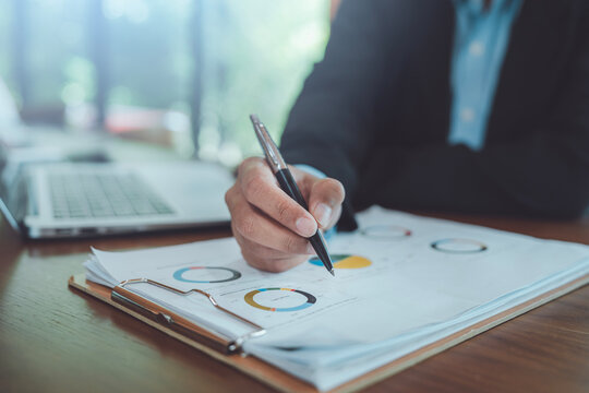 Financial data analysis concept businessman hand pointing pen at pie chart reviewing corporate business strategy report market trend statistics performance audit management