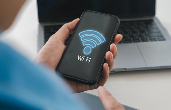 Person holding smartphone with glowing blue wifi icon on screen. Fast wireless internet connection, modern mobile network technology, digital communication and global smart device connectivity
