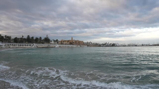 Moody seascape at Monastir, Tunisia, the fort ribat and Mediterranean sea under dramatic storm clouds and soft light, conveying tranquility, travel mood, and coastal atmosphere