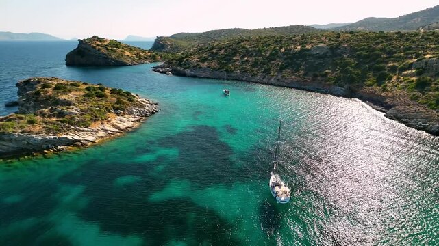 Scenic drone shot of green mountains surrounding sailing anchoring bay
