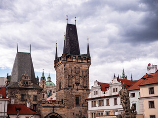 Obraz premium Lesser Town Bridge Tower and Judith Tower near Charles Bridge with St. Nicholas Church in the background under dramatic cloudy sky in Prague, Czechia.