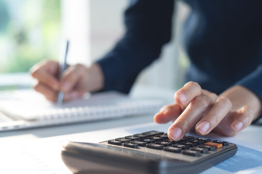 Business finance accounting banking concept. Businesswoman doing finances, using calculator to calculate business report on desk at office, budget planning, tax calculation