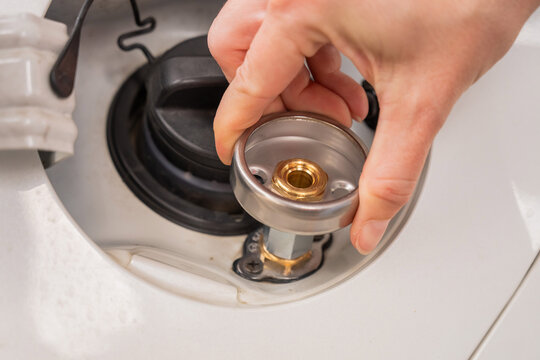 A woman installs an adapter on a gas tank in a car.