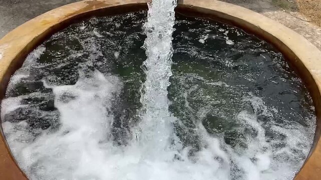 Water rushing into concrete well with splashing foam
