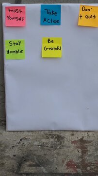 Colorful Sticky Notes with Motivational Quotes Displayed on White Poster Board