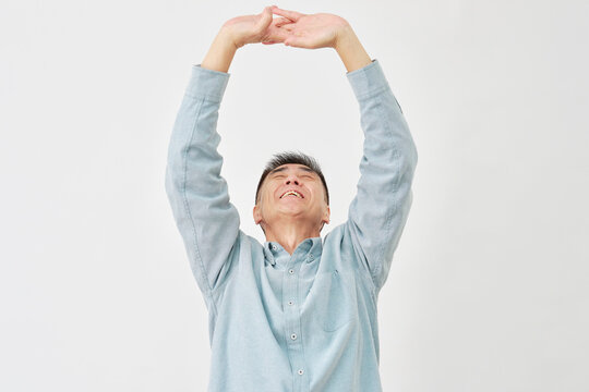 白背景で伸びをする高齢男性