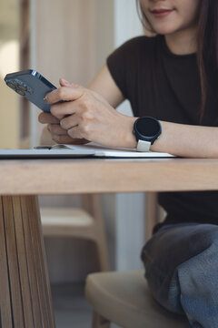 Closeup, young asian woman reading message on smartphone and working on laptop at cafe office, Freelancer remote working via laptop at home office, online job, business casual lifestyle, vertical