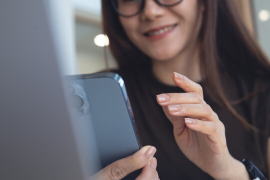 Closeup, asian woman smiling and using mobile phone, online messaging on social network while remote working on laptop at home. 