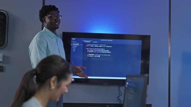 African male developer provides personalized technical guidance and code explanation using AI documentation tools, demonstrating expertise and knowledge transfer in development environment.