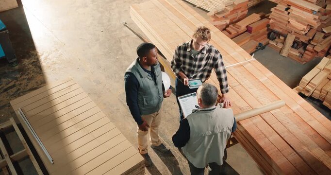 Carpenter, team and planning above for manufacturing, timber inventory or quality control clipboard. Production, woodwork or talk with men in warehouse for joinery project, tablet or stock inspection