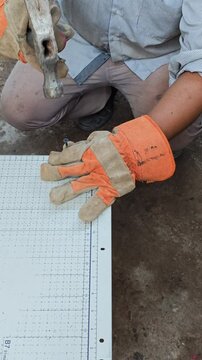 Hands Using Hammer to Drive Metal Screw into Sheet Plate