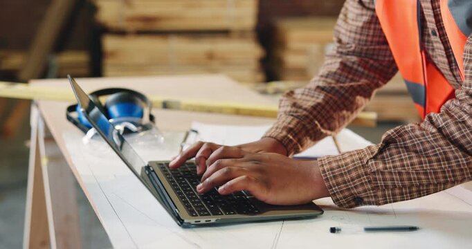 Carpenter, workshop and hands of man on laptop for furniture order, project schedule or email. Contractor, computer and person typing for planning, report or timber inventory for woodworking business