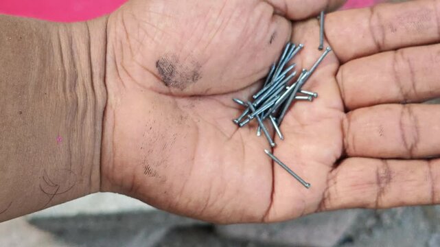 Close Up of Small Metal Nails Held in Open Palm