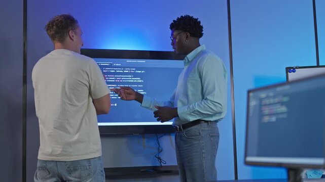 Diverse male developers engage in peer-level code review using AI-assisted tools for real-time optimization and collaborative code architecture discussion.